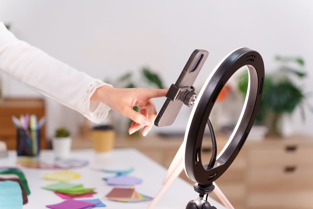 influencer recording on phone, phone pllaced in a ring light
